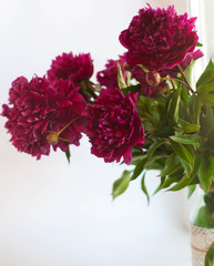 selective focus of bouquet with pink peonies and green leaves near window at home