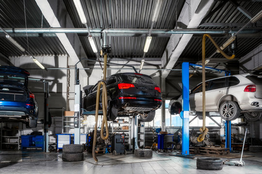 Car repair on a lift for the repair of the chassis, automatic transmission and engine in the auto repair shop or garage. Car workshop concept