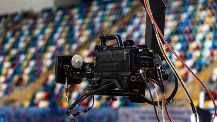 A television camera on a crane outside the studio. The video camera hanging on the crane prepares for a live sporting event. The live broadcast is very popular. Television cameras are an important