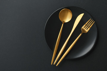 Gold cutlery set on black background - obrazy, fototapety, plakaty