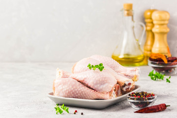 Raw chicken legs, pepper, olive oil on concrete background. Selective focus, space for text.