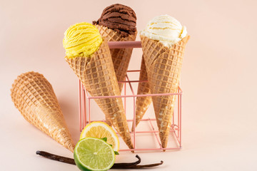 Assorted ice cream in sugar cones on pink background.