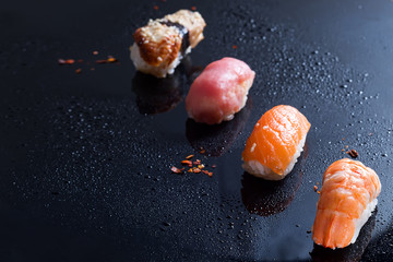 Sashimi, uramaki and nighiri, Japanese dish consisting of rice, salmon or tuna, shrimp in black with water drops . Concept of Japanese restaurant, Flat lay copy space © YuliiaMazurkevych