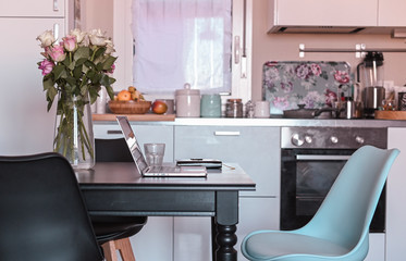 Computer on the table in the kitchen. Work at home and freelance. Cozy home. Free space for text.