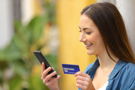Happy woman paying online using credit card and phone