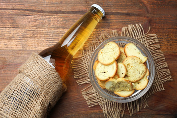bottle with light beer and bowl with crackers