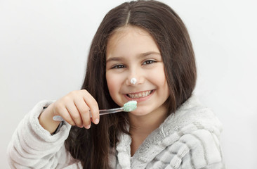 Happy cute little child girl brushing her teeth on white background. Space for text. Healthy teeth. 