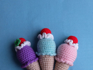 Knitted multicolored ice cream toys against blue background