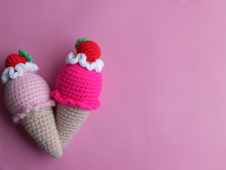 Knitted multicolored ice cream toys against pink background