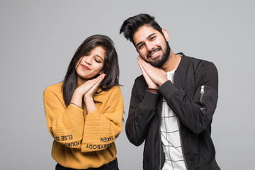 Young couple, indian man and woman with sleep sign on gray background