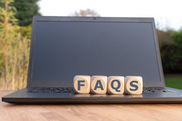 Cubes on a notebook form the abbreviation "FAQS".