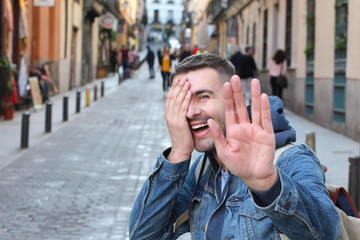 Shy man covering his face while smiling 