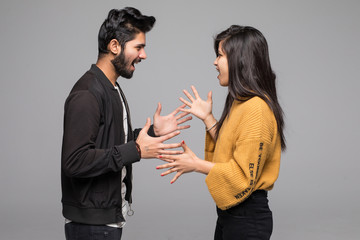 Angry indian couple shouting at each other quarrel on gray background