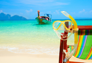 Summer beach paradise, diving mask and snorkel on a wooden chair on a background of blue sea
