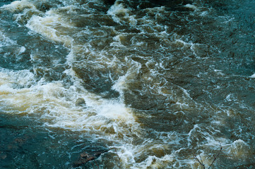 Background, top view, fast flowing river with dark blue water and white foam waves