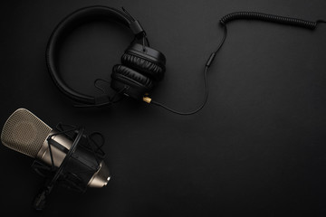 Studio microphone with headphones on a black background.Flat lay.Concept Radio, broadcasting, blog,...