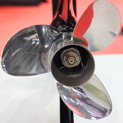 Close up stainless steel motor boat propeller on drive shaft of outboard motor - rear view