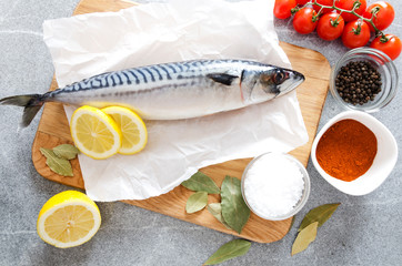 Mackerel on cutting board with different herbs and vegetables. Concept of cooking fresh fish for dinner, top view