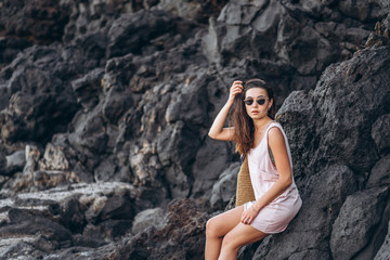 Naklejka premium Pretty long hair brunette tourist girl relaxing on the stones near sea.