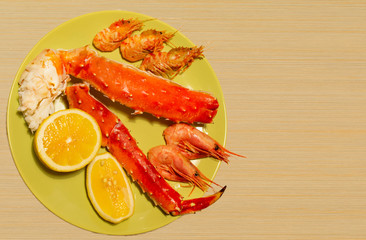 boiled king crab, shrimps in a plate on a wooden background