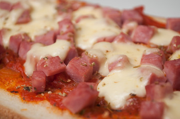 closeup of homemade Bruschetta with ham cubes and cheese in a white plate