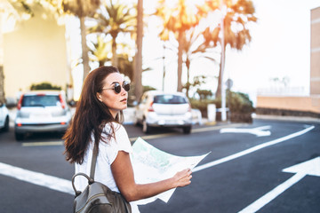 Pretty brunette tourist girl with map in hands on the street searching way.