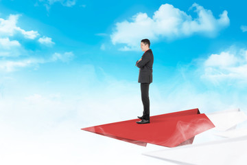 Handsome asian businessman standing on paper plane flying