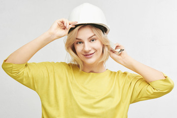 Portrait of young sexy blond woman engineer in construction helmet posing, gently smiling at camera isolated on white background in studio