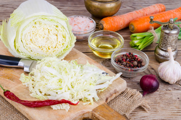 Sliced Chinese cabbage, carrots, spices for cooking on wooden board.