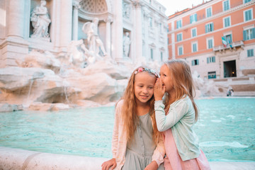 Adorable little girls on the edge of Fountain of Trevi in Rome.