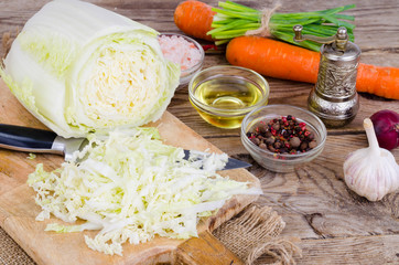 Sliced Chinese cabbage, carrots, spices for cooking on wooden board.