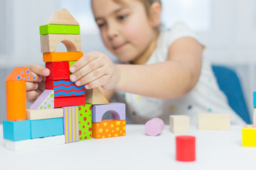 Children play with educational toy on table in the children's room. Two kids playing with colorful blocks. Kindergarten educational games