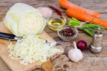 Sliced Chinese cabbage, carrots, spices for cooking on wooden board.