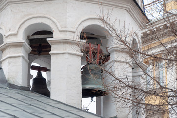 Bells of the orthodox bell tower partially hidden by the trees in the winter