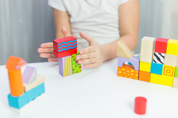 Schoolgirl girl play with educational toy on table in the children's room. Two kids playing with colorful blocks. Kindergarten educational games