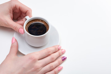 Woman's hands holding cup of espresso, white background
