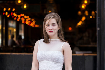 Medium shot of beautiful young woman in cropped white top with windswept hair and soft focus light background