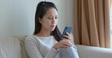 Woman apply paper mask on face at home with use of mobile phone