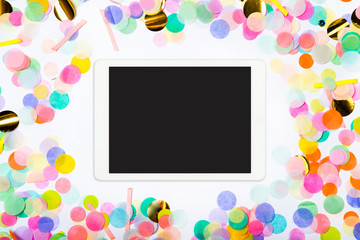 Touchpad with blank screen on colorful confetti background. Color party background with touchscreen...