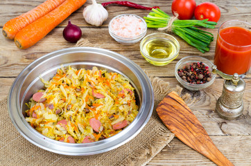 Fried sauerkraut with sausages in metal bowl.