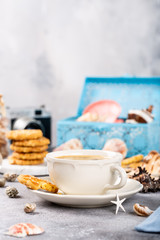 Cup of coffee and biscuits with seashells and decorations. Dreams of sea vacation and concept. Copy space.