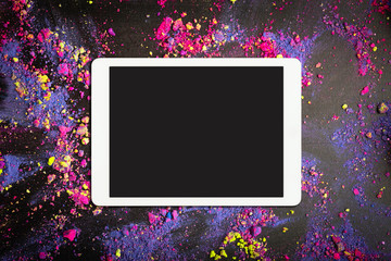 Touchpad with blank screen on colorful crumbled eyeshadows or holi colors on black background....