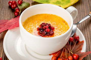 Yellow soup decorated with rowan in a white plate