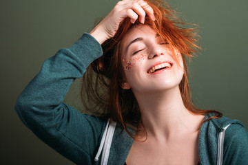 Cute young woman portrait. Fun and happiness. Redhead female messing hair. Toothy smile. Eyes...