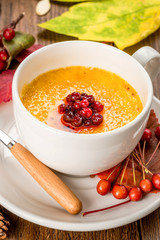 Yellow soup decorated with rowan in a white plate