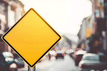 Empty yellow traffic sign on blur traffic road with colorful bokeh light abstract background.