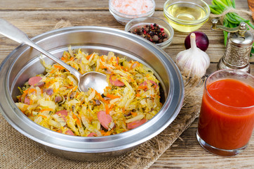 Fried sauerkraut with sausages in metal bowl.