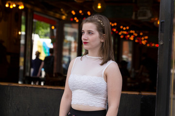 Medium shot of beautiful young woman in half profile with lighted restaurant in soft focus background