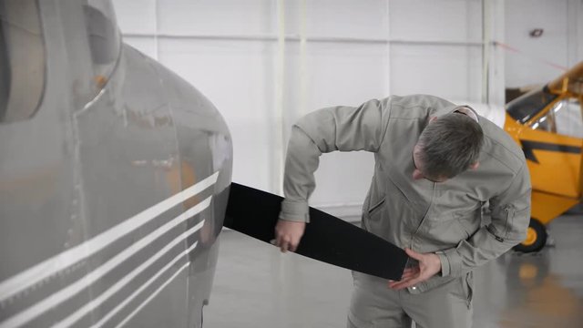 Caucasian male aviator carefully cleaning propeller