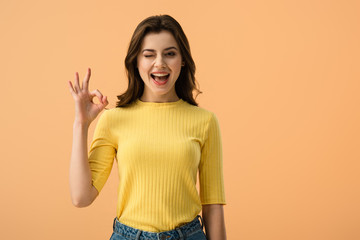 cheerful brunette girl showing ok sign isolated on orange